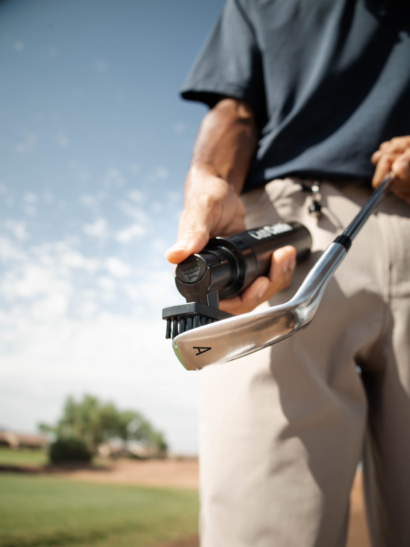 Golfer cleaning the grooves of a wedge with the Club Caddie Brush